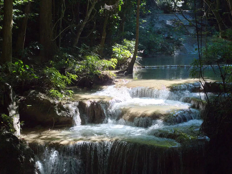 A waterfall flowing through green forest in Tha Kradan, Kanchanaburi